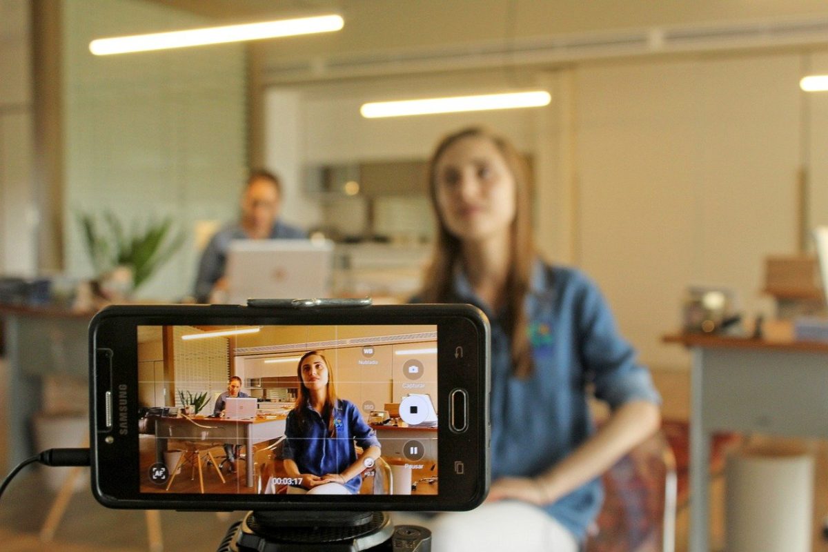 Smartphone camera turned horizontally filming a local business with woman in the foreground and a woman in the background