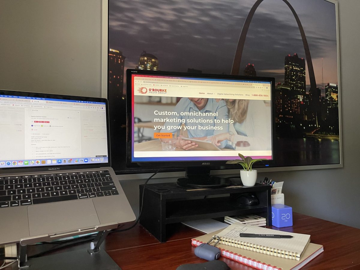 Megan’s desk setup to help her thrive in a remote job, with two computers on laptop stands near pads of paper and pen